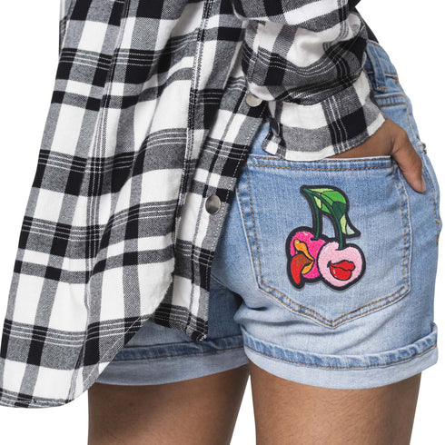 Patch featuring two cherries with expressive lips, one with a tongue sticking out, set against a white background. The design is playful and vibrant, combining bold colors with a fun, cheeky style.
